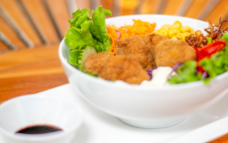 PalmBeach Tropical Restaurant | Chicken and Rice Poke | bowl of rice with breaded chicken bits (eggs and toast), corn, cucumbers, green salad, purple cabbage, fried onions, sesame seeds, garlic mayonnaise and served with soy sauce on the side
