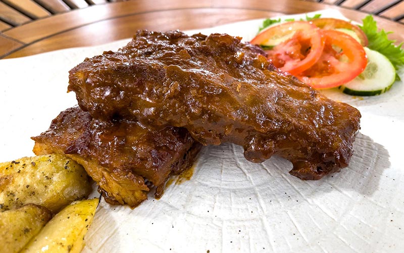 PalmBeach Tropical Restaurant | Pork Ribs in BBQ Sauce | pork ribs cooked at a low temperature in bbq sauce and served with our baked potatoes